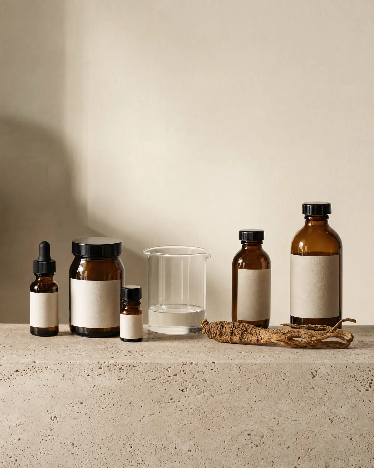 Amber bottles, a glass beaker and dried roots on a travertine shelf